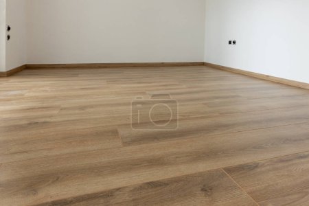 Foto de Suelo de madera laminada con pared blanca. Habitación vacía con laminado flotante en nuevos apartmen - Imagen libre de derechos