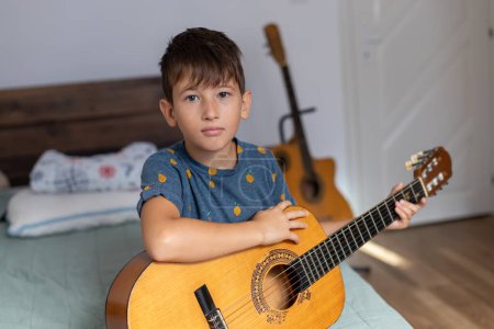 Foto de Niño con guitarra acústica en su habitación. - Imagen libre de derechos