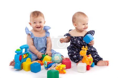 Foto de Dos niñas lindas jugando con juguetes, aisladas en blanco. Divertirse, sonreír - Imagen libre de derechos
