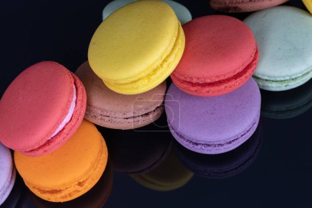 Téléchargez les photos : Beaucoup de macarons colorés sur fond noir avec réflexion. Dessert traditionnel français - en image libre de droit