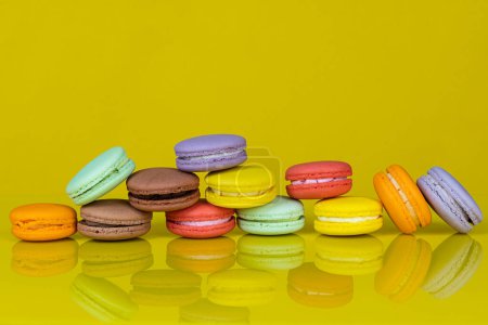 Téléchargez les photos : Beaucoup de macarons colorés sur fond jaune avec réflexion. Dessert traditionnel français - en image libre de droit
