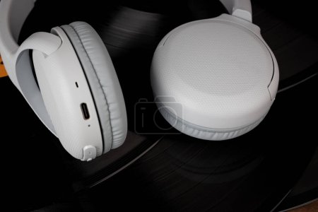 Photo for White wireless headphones on old vinyl records. Music concept. Rretro sound system - Royalty Free Image