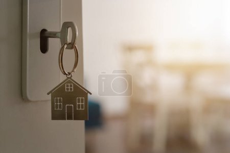 Téléchargez les photos : Porte ouverte sur une nouvelle maison avec porte-clés et porte-clés en forme de maison. Hypothèque, investissement, immobilier, immobilier et concept de maison neuve - en image libre de droit