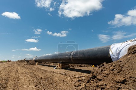 Foto de Construcción de gasoductos y oleoductos. Tubos soldados juntos. El oleoducto está en construcción. Cielo nublado - Imagen libre de derechos