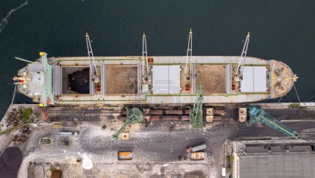 Téléchargez les photos : Loading dry cargo ship of brown sugar by cranes in port. Aerial view loading into holds of sea cargo vessel - en image libre de droit