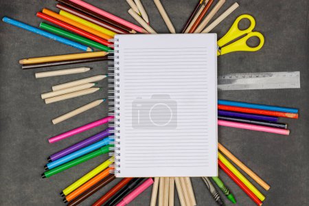 Téléchargez les photos : Fournitures scolaires colorées sur tableau noir. Bloc-notes vierge avec divers crayons, marqueurs et crayons. Concept de retour à l'école. - en image libre de droit