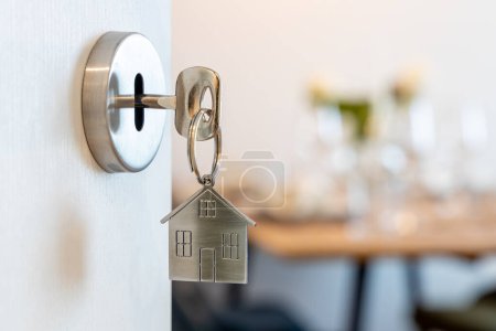 Téléchargez les photos : Porte ouverte sur une nouvelle maison avec porte-clés et porte-clés en forme de maison. Hypothèque, investissement, immobilier, immobilier et concept de maison neuve - en image libre de droit