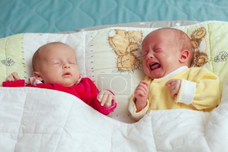 Photo pour Two adorable twin babies sleeping,  one crying. Closeup portrait, caucasian child - image libre de droit