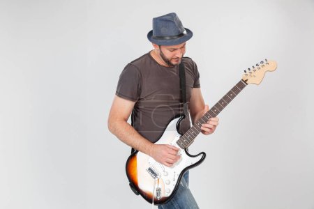 Téléchargez les photos : Homme avec chapeau et barbe jouer sur guitare électrique avec enthousiasme. - en image libre de droit