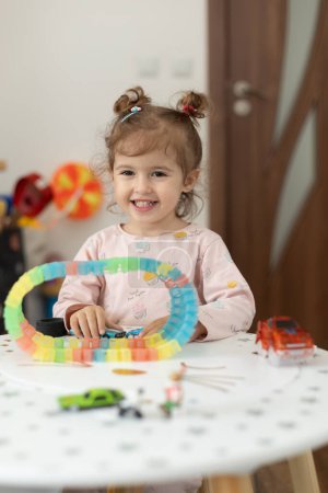 Foto de Niña feliz jugando con juguetes en la mesa en casa. Actividades en casa. Infancia - Imagen libre de derechos