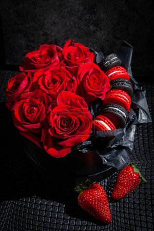 Foto de Caja de regalo con rosas rojas y macarrones, decorada con fresas. Antecedentes para el día de San Valentín y la mujer. Decoración de boda - Imagen libre de derechos