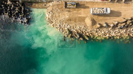 Téléchargez les photos : Vue aérienne du chantier riverain avec pelle. Bulldozer travaillant sur une construction de brise-lames - en image libre de droit