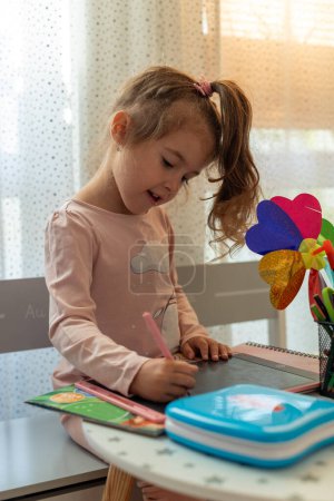 Téléchargez les photos : Jolie petite fille aime peindre. Fille dessin et coloriage image sur tablette dans sa chambre à la maison - en image libre de droit