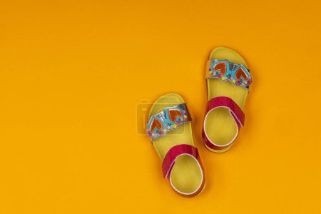 Téléchargez les photos : Jolies sandales pour enfants sur fond jaune. Sandales petite fille - en image libre de droit