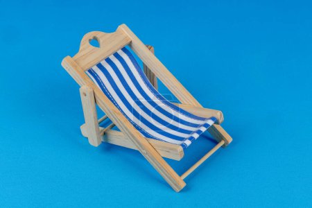Foto de Silla de playa sobre fondo azul. Silla de cubierta rayada azul y blanca. - Imagen libre de derechos