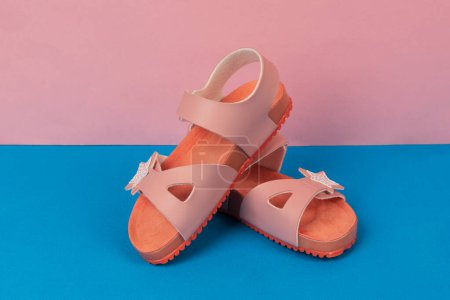 Two pink sandals on pink, blue background. Cute pink sandals for little girl.