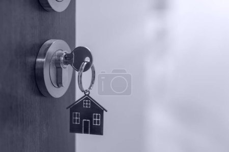 Foto de Puerta abierta a un nuevo hogar con llave y llavero en forma de hogar. Hipoteca, inversión, bienes raíces, propiedad y nuevo concepto de hogar - Imagen libre de derechos