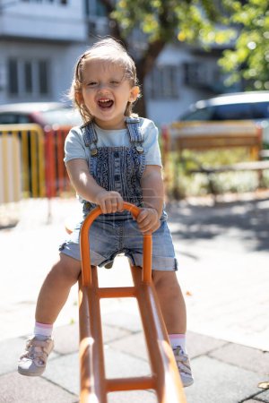 Foto de Niña feliz divirtiéndose en el patio al aire libre. Balanceo en swing. - Imagen libre de derechos
