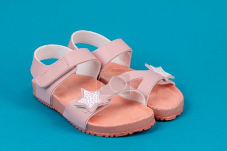 Foto de Dos sandalias rosas sobre fondo azul. Lindas sandalias rosadas para niña. - Imagen libre de derechos