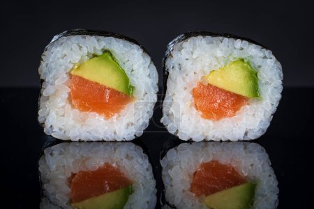 Téléchargez les photos : Rouleaux de sushi au thon et à l'avocat. Sushi avec réflexion. Nourriture japonaise traditionnelle - en image libre de droit