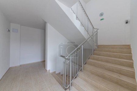 Foto de Escalera moderna entre pisos. Escaleras con riel metálico en edificio moderno - Imagen libre de derechos