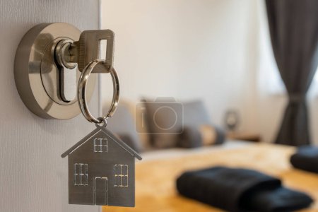 Foto de Puerta abierta a un nuevo hogar con llave y llavero en forma de hogar. Hipoteca, inversión, bienes raíces, propiedad y nuevo concepto de hogar - Imagen libre de derechos