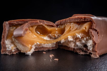 Téléchargez les photos : Gros plan de barre chocolatée avec remplissage au caramel, cassé en deux - en image libre de droit