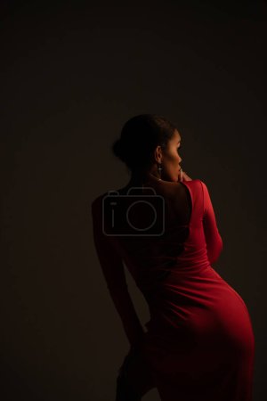 Photo for Stylish woman in a beautiful pink dress. View from the back. Fashion dark portrait of a woman. - Royalty Free Image