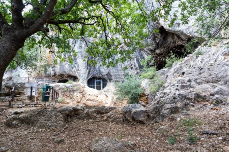 Foto de Entrada a una cueva con rocas, árboles verdes en el Parque Nacional, un museo al aire libre. Situado cerca de la ciudad de Antalya, Turquía - Imagen libre de derechos