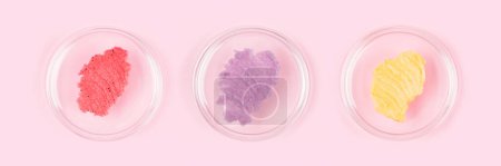 Foto de Pink red, purple and yellow scrub smudges in petri glass dishes over pastel pink background. Sugar body scrub smears. Long horizontal banner - Imagen libre de derechos