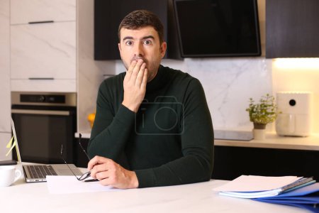 Foto de Retrato de joven guapo que trabaja desde casa con el ordenador portátil en la cocina - Imagen libre de derechos