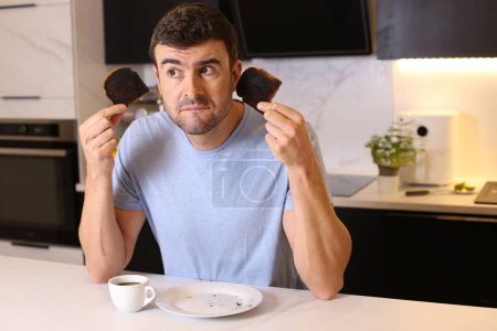 Photo for Portrait of handsome young man with overcooked toasts at kitchen - Royalty Free Image