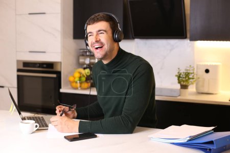Photo for Portrait of handsome young man with headset and laptop working at kitchen - Royalty Free Image