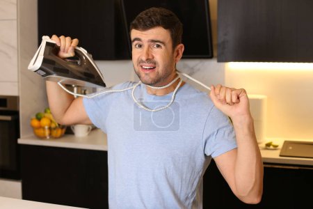 Foto de Retrato de joven guapo ahogándose con alambre de hierro en la cocina - Imagen libre de derechos