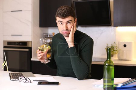 Photo for Portrait of handsome young man with glass of wine working from home at kitchen - Royalty Free Image