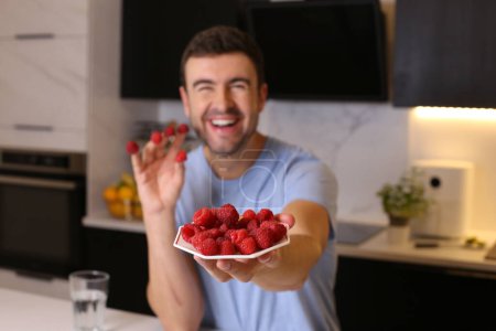 Photo for Portrait of handsome young man with raspberries at kitchen - Royalty Free Image