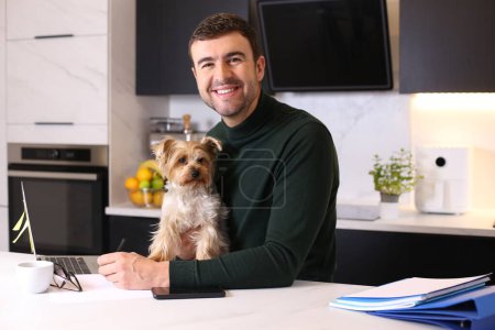Foto de Retrato de joven guapo con su lindo perrito en la cocina - Imagen libre de derechos