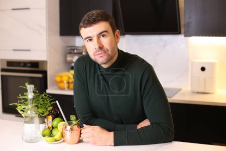 Téléchargez les photos : Portrait de beau jeune homme avec limes et boisson à la menthe à la cuisine - en image libre de droit