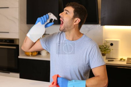 Téléchargez les photos : Portrait de beau jeune homme avec des fournitures de nettoyage à la cuisine - en image libre de droit
