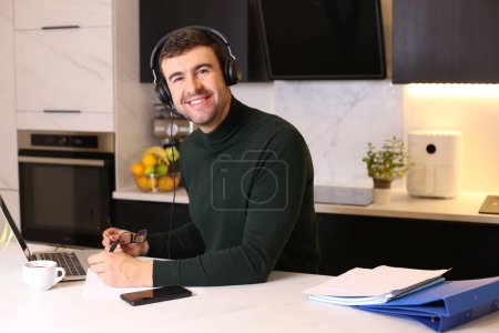 Photo for Portrait of handsome young man with headset and laptop working at kitchen - Royalty Free Image