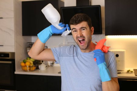 Foto de Retrato de joven guapo con artículos de limpieza en la cocina - Imagen libre de derechos