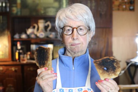 Photo for Close-up portrait of mature woman with overroasted toasts at home - Royalty Free Image