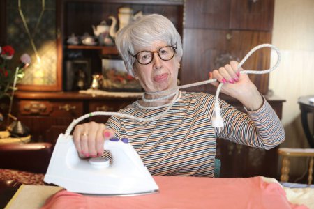 Photo for Close-up portrait of mature woman ironing clothes at home - Royalty Free Image