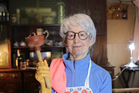 Foto de Close-up portrait of mature woman in apron cleaning her home - Imagen libre de derechos