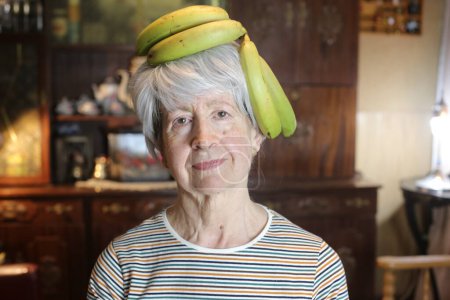 Photo for Close-up portrait of mature woman with branch of bananas at home - Royalty Free Image