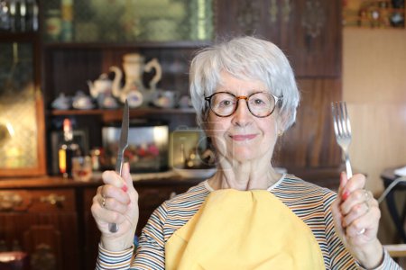 Foto de Close-up portrait of mature woman with cutlery and napkin at home - Imagen libre de derechos