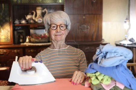 Photo for Close-up portrait of mature woman ironing clothes at home - Royalty Free Image