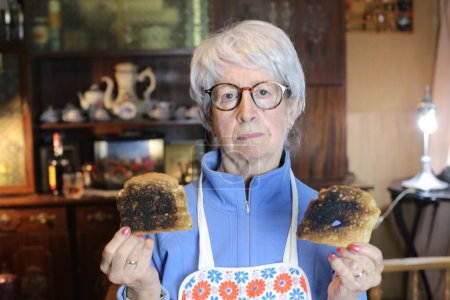 Photo for Close-up portrait of mature woman with overroasted toasts at home - Royalty Free Image