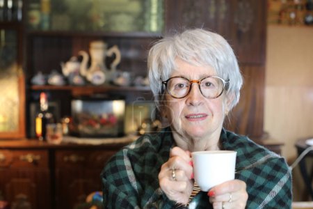 Foto de Close-up portrait of mature woman with cup of hot drink at home - Imagen libre de derechos
