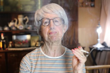 Foto de Close-up portrait of mature woman smoking cigarette at home - Imagen libre de derechos